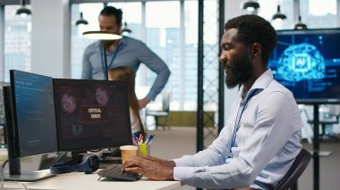 Ofisteki programcı kritik hata uyarısını düzeltmek için iş arkadaşlarından yardım istiyor. BT çalışanı ve meslektaşları, bilgisayar hatasının nasıl düzeltileceği konusunda fikir alışverişinde bulunuyorlar.