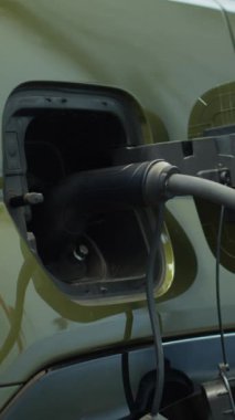 Otoparkta şarj edilecek elektrikli motora güç veren EV akünün dikey videosu. Elektrikli araba aküsü şarj etmek için temiz enerji kaynağına takıldı, el kamerası görüntüsü