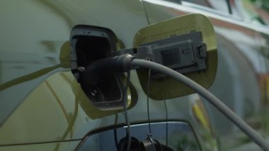 Uzun yolculuktan önce şarj etmek için EV vagonuna bağlı elektrik kablosunu kapat. Elektrikli otomobilin araç giriş portu temiz enerji elektriği kullanarak dolum yapmak için kullanılır