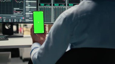 Borsacı yatırımları geliştirmek için krom anahtar telefonu kullanarak finansal analiz yapıyor. Hisse senedi piyasa değerini değerlendirmek için izole ekran akıllı telefonu kullanan varlık yönetimi çalışanı