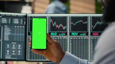 Pervane firma ofisindeki tüccar yeşil ekran cep telefonu kullanarak sanal toplantıya katılıyor. İnternet telekonferansına katılmak için krom anahtar cep telefonu kullanan Afro-Amerikalı adam, kamera B