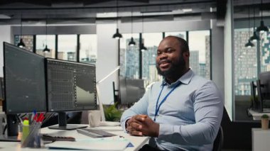 Yüksek getirili portföy operasyonlarıyla turnayı gözünden vurduktan sonra gülümseyen borsa simsarı portresi. Neşeli Afrikalı Amerikalı adam yatırım kilometre taşlarına ulaştıktan sonra seviniyor, kamera A