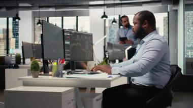 Pervane firması ofisindeki portföy yöneticisi yatırım iadelerini artırmak için borsa eğilimlerini analiz ediyor. Afrikalı Amerikalı adam yatırım olanaklarını belirlemek için performans ölçümlerini takip ediyor, kamera A