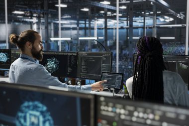 Yüksek teknoloji veri merkezindeki yöneticiler yapay zeka teknolojisinin yardımıyla yükseltilmiş sunucu rafları kuruyorlar. Sunucu odası bilişim uzmanları yapay zeka kullanarak şirket ağlarını güncelliyorlar.