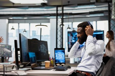 Ofisteki programcı, yapay zekaya cihazlar üzerinden görevler yürütmesi, ekranlardaki ilerlemeyi izlemesi, müzik dinlemesi konusunda güveniyor. Bilgi işlem uzmanı kulaklık takıyor, yapay zeka geliştirmek için bilişim donanımı kullanıyor.