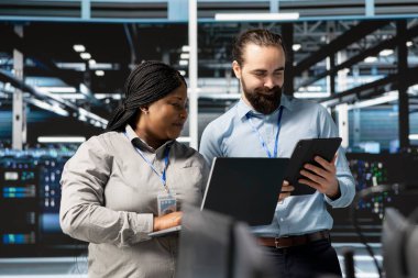 Veri merkezindeki mutlu sistem yöneticileri güvenlik duvarı yapılandırmalarını doğrulayan cihazlar kullanıyorlar. Jolly takım çalışması bilişim uzmanları sunucu merkezinde ekipman savunmasızlığı taraması yapıyor