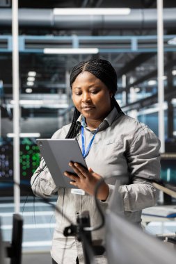 Veri merkezindeki kadın yazılım güncellemeleri yapıyor, derin öğrenme parametrelerini doğruluyor. Yapılandırmaları denetlemek ve en iyi uygulama performansını sağlamak için PC kullanan Afrikalı Amerikalı sunucu merkezi IT uzmanı