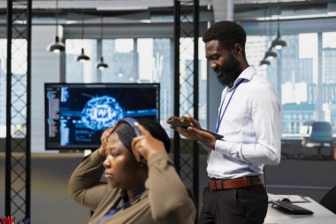 Bilgisayar bilimcisi, tablet kullanarak performansı optimize etmek için yapay zekayı kullanıyor. Ofis eğitim makinesinde çalışan Afrikalı Amerikalı mühendis cihazla modelleri öğreniyor