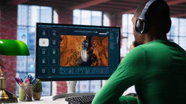 Zenci adam, üretken bir ev ortamında mesajlardan video görüntüsü üretmek için derin öğrenme araçları kullanıyor. Freelancer üretken yapay zeka montajı için bilgisayar kullanır. Kamera A.
