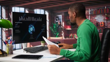 Siyah serbest çalışan, iş konferansını PC monitöründen izliyor, istatistik tablolarına bakıyor. Apartman ofisindeki uzaktan çalışan bilgisayardaki sunum grafiklerini takip ediyor. Kamera B.