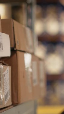 Siyahi işçilerin endüstriyel raflardaki kargo etiketlerini işlemek için barkod tarayıcısı kullandıkları dikey video. İz sürme bilgisi ve lojistik ile paket izleme servisi için yanlış etiketler taranıyor