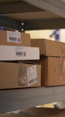 Siyahi işçilerin endüstriyel raflardaki kargo etiketlerini işlemek için barkod tarayıcısı kullandıkları dikey video. İz sürme bilgisi ve lojistik ile paket izleme servisi için yanlış etiketler taranıyor