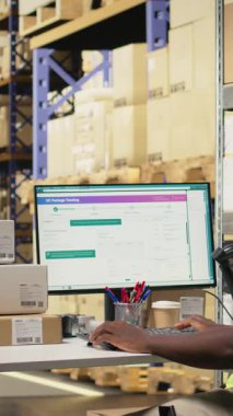 İthalat işlemi sırasında kargo mallarını doğrulayan dikey video depo çalışanları. Yelek ve miğfer giyerken dağıtım merkezindeki düzgün takip numaralarını yönetiyordu. Kamera A.