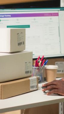 Dikey Afrikalı Amerikalı katip, büyük sanayi raflarındaki kutuların sevkiyat detaylarını kaydetmek için barkod tarayıcısı kullanıyor. Paket izleme servisi için havayolu faturaları taranıyor, doğru lojistik