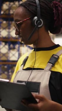 Dikey Video Siyah kadın çalışanları lojistik merkezdeki müşteri hizmetlerine cevap veriyor paketler için sipariş takibi, yanlış adres sorununu çözme ve nakliye detaylarını güncellemede yardımcı oluyor. Yardım hattı