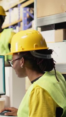 Dikey Video Afrikalı Amerikalı kadın awb etiketlerinin sevkiyat detaylarını doğruluyor, paket takip yazılımını kullanarak doğru sipariş statüsüne sahip. Depo içindeki ithalat işlemleri denetleniyor