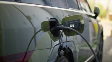 Modern istasyonda elektrikli cipin şarj olurken yakın plan çekimleri temiz enerji taşımacılığını gösteriyor. Elektrikli arabaya bağlı EV prizi, çevre dostu teknoloji kavramı, el kamerası görüntüsü