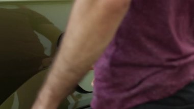 Sürücünün EV otomobil aküsünü şarj ettiği yeşil teknolojili elektrikli motoru kapatın. Adam alternatif enerji kaynağına takılarak EV arabanın bataryasını şarj ediyor