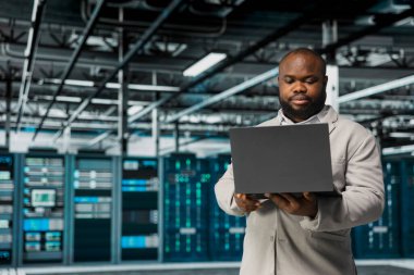 Sunucu merkezindeki altyapı sistemlerini yöneten teknisyen dizüstü bilgisayardaki kurtarma planını kontrol ediyor. Veri merkezi çalışanı, araçları kullanarak performansı izlemek, platformların optimum olarak çalıştığından emin olmak