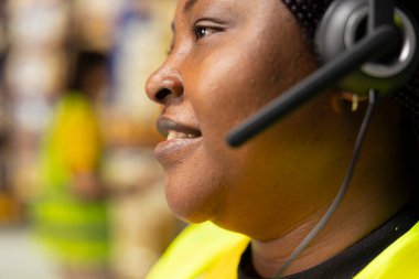 Kadın müşteri destek katibi müşterilerle sevkiyat detayları hakkında konuşur, yardım hattında yanlış adres karışıklığına yardım eder. Kadın siparişi çözer, hava yolu faturalarını onaylar..