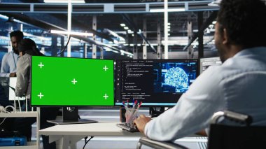 Parapleji yapan veri merkezi mühendisi yeşil ekrandaki yapay zeka öğrenme algoritmalarını kullanarak veri tabanlarını analiz ediyor. Krom anahtar bilgisayarında sunucu odası çalışanı yapay zeka ağları kullanıyor. Kamera A.