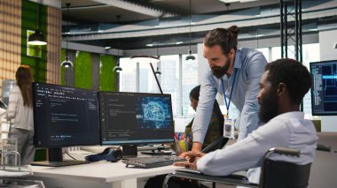 Parapleji beyin fırtınası yapan, makine öğrenme teknolojisiyle çalışan bir mühendis ve iş arkadaşı. Tekerlekli sandalyedeki adam ve ofisteki iş arkadaşı verileri yapay zeka öngörücü modellere dönüştürüyor, kamera A