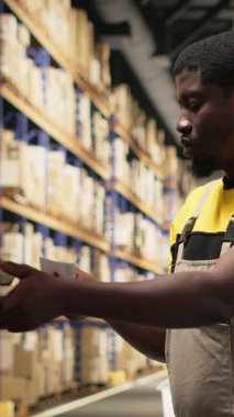 Dikey Video Kadını çalışanı, ambardaki kutulara yapışkan nakliye etiketleri yapıştırıyor, paketleri yanlış takip numaralarıyla etiketliyor ve sorunsuz ekspres teslimat ve sipariş işlemlerini sağlama alıyor. Kamera B.