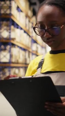 Dikey Afrikalı Amerikalı kadın lojistik sistem, dağıtım merkezi, raflar ve nakliye protokolleri için ticari verileri inceliyor. Perakende satış ve tedarik zinciri