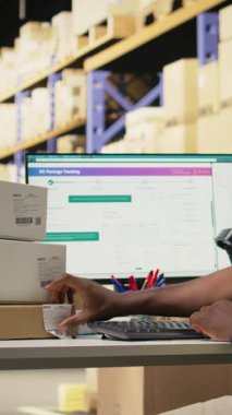 Dikey Video Afrikalı Amerikalı işçi hava yolu faturası detaylarını uyguluyor ve kutulardaki etiketleri tarıyor. Paket takibi, yanlış etiketler ve kayıtlar büyük işletmeler için nakliye işlemleri. Kamera A.