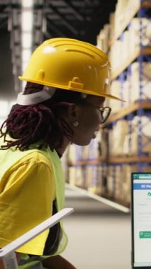 Dikey Video Siyah çalışanları kalabalık depo ortamında paket sevkiyatı takım çalışmasından gurur ve memnuniyet duyarak bir beşlik jest paylaşıyorlar. Verimliliği sağlamak için görevler zamanında bitiriliyor