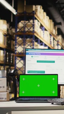 Dikey Video Stok odası çalışanı, elektronik ticaret büyük işletmeleri için ithalat işlemleri yürüten bilgisayar yazılımındaki paketleri takip ederek, fotokopi alanındaki telefona bakıyor. Depoda sipariş tamamlama