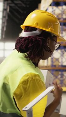 Dikey Video Afrikalı Amerikalı işçiler, ithalat işlemleri için sanayi deposunda çalışan bir paket izleme yazılımının paket statüsünü sağlıyorlar. Envanter ve sevkiyat protokolü yönetiliyor