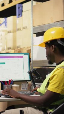 Dikey Video Siyah elemanı, endüstriyel depolama raflarındaki kutulardaki nakliye etiketlerini işlemek için bir barkod tarayıcısı kullanıyor. Paket izleme servisi ve doğru lojistik için awb etiketleri taranıyor