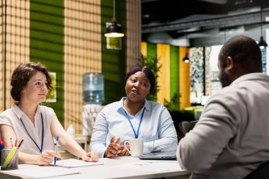 İş bulma sürecinde insan kaynakları ekibinin karşısında oturan siyahi iş arayan, iş tecrübesini ve iş kurumu iş teklifi niteliklerini sunan kişi. Kariyer hedefleri.