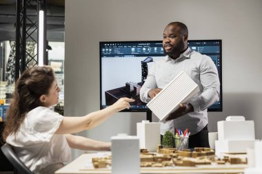 Tasarım için mimari 3D modeller sunan siyah erkek mühendis, stratejik yeniden geliştirme projesinin ana planıyla planlar oluşturuyor. Altyapı büyümesi için ikamet alanı.