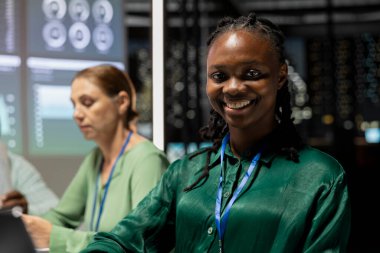 Gülümseyen siyahi yönetici yardımcısı önemli bir toplantıya hazırlanıyor, saatler sonra kalkınma fonlarını artırıyor. İş arkadaşları hedef belirleme tartışmasına katıldı.