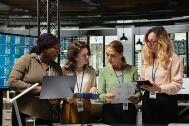 Çok ırklı meslektaşlar, iş stratejisini, dizüstü bilgisayardaki performans verilerini ve başarı, ilerleme ve ortak hedefler etrafında sıralanmış belgeleri analiz eden güçlü bir ekip oluştururlar..