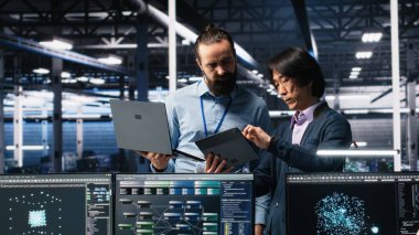 Veri Merkezi Yöneticisi, AI LLM 'leri izlemek için aygıt kullanan geliştiriciyi denetliyor. Ekip lideri, sunucuları denetleyen, makine öğrenme süreçlerini çalıştıran, kamera A tarafından yapılan işlemi kontrol ediyor.