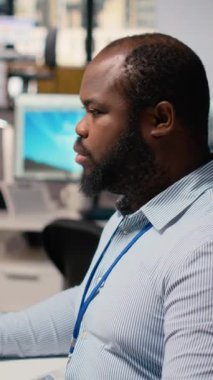 Ofiste rüzgar türbini simülasyonu üzerinde çalışan bir teknisyen güncelleme yapıyor. Ar-Ge departmanındaki Afrikalı Amerikalı adam bilgisayarda CAD yazılımı kullanıyor, yenilenebilir enerji yel değirmeni mühendisliği yapıyor, kamera B