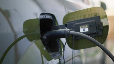Otoparktayken EV çevre dostu arabanın şarj edilişini yakından çek. Yenilenebilir enerjiyi emisyonsuz olarak kullanarak şarj edilebilir pille donatılmış elektrikli araç takın