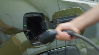 Çevre dostu sürücü, şarj olduktan sonra iskele tarafındaki elektrikli arabayı şarj ederek kapatıyor. Yeşil enerji geçişi kavramı. Elektirik kablosunu EV aracından ayıran adam, şarjı bitiyor, kapat