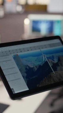 Rüzgâr türbini CAD tasarımı üzerinde çalışmak için tablet kullanarak sürdürülebilir enerji araştırması yaparak, ofisteki mühendisi kapat. A kamerasında rüzgar enerjisi jeneratörünün dijital modellemesini yapan işçiler.