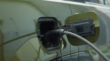 Sıfır emisyon teknisyeni kavramı olan EV 'yi şarj ettikten sonra otoparktan ayrılmaya hazırlanan sürücünün yakın çekimi. EVSE istasyonunda şarj ettikten sonra elektrikli araç giriş portunu kapatan adam