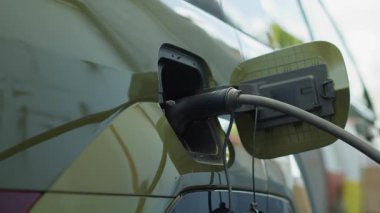 Modern istasyonda elektrikli aracın şarj olurken yakın plan çekimleri temiz enerji taşımacılığını gösteriyor. EV prizi elektrikli arabaya bağlı, çevre dostu teknoloji kavramı