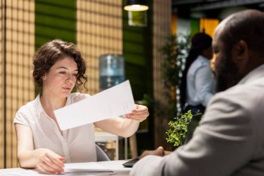 İnsan Kaynakları uzmanı, adayların gözden geçirmesi için sözleşmenin detaylarını kontrol etmek üzere iş imkanları paketini teslim ediyor. Emeklilik planları ve sağlık programları sunan şirket.