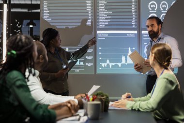 Ticari faaliyetleri değerlendirmek, finansmanı artırmak ve çok uluslu şirketi geliştirmenin yolları üzerinde çalışmak için veri içgörülerini inceleyen çok ırklı personel üyeleri. Gece Danışma Kurulu.