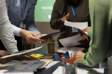 Saatler sonra, çok ırklı bir grup strateji odasında toplanıp, görsel verileri, istatistikleri ve risk değerlendirme dosyalarını analiz ederek, proje gelişimini verimlilik için ileriye taşır..