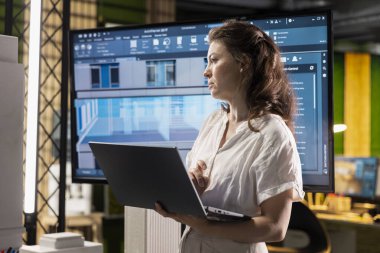 Kadın emlak müteahhidi, kentsel planlama, site hazırlama ve modern bir konut projesi için yapısal konut tasarımı için kullanılan 3D araçlar ve dijital planlarla çalışıyor..