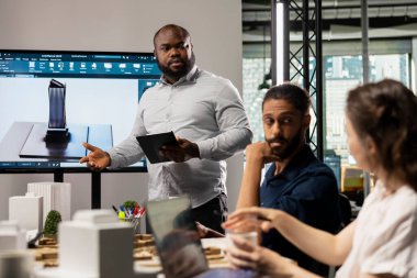 Çeşitli geliştiriciler inşaat ve şehir planlaması için yenilikçi tasarım fikirleri üretiyor, altyapı büyüme projesinin onaylanmasını sağlamak için bir toplantı odasında emlak uzmanları toplanıyor..