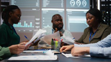 Arşivlenmiş dosyalardaki veri numaralarını değerlendiren, strateji odasında gece geç saatlerde net girişimcilik hedefleri belirlemek için raporları ve görüşleri paylaşan çeşitli uzmanları kapatın. Kamera A.